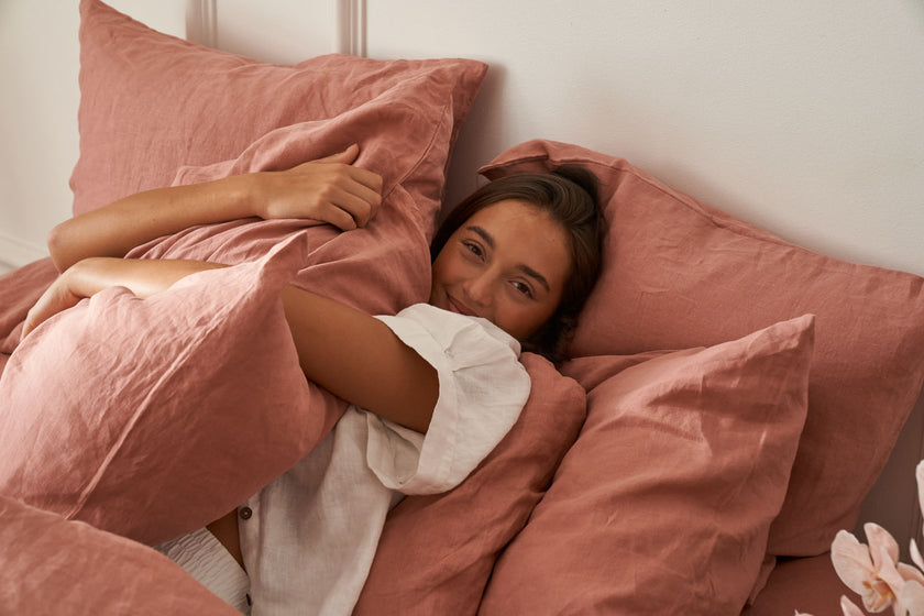 Model lying in bed with our Rosa sheets and pillow set